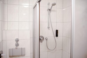 Une douche moderne dotée d’un pommeau de douche à main et d’un robinet mural.