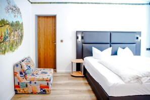 Une chambre à coucher avec un lit, une porte en bois, une petite table et un canapé coloré.
