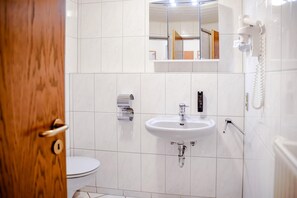 Et badeværelse med toilet, håndvask og spejl.