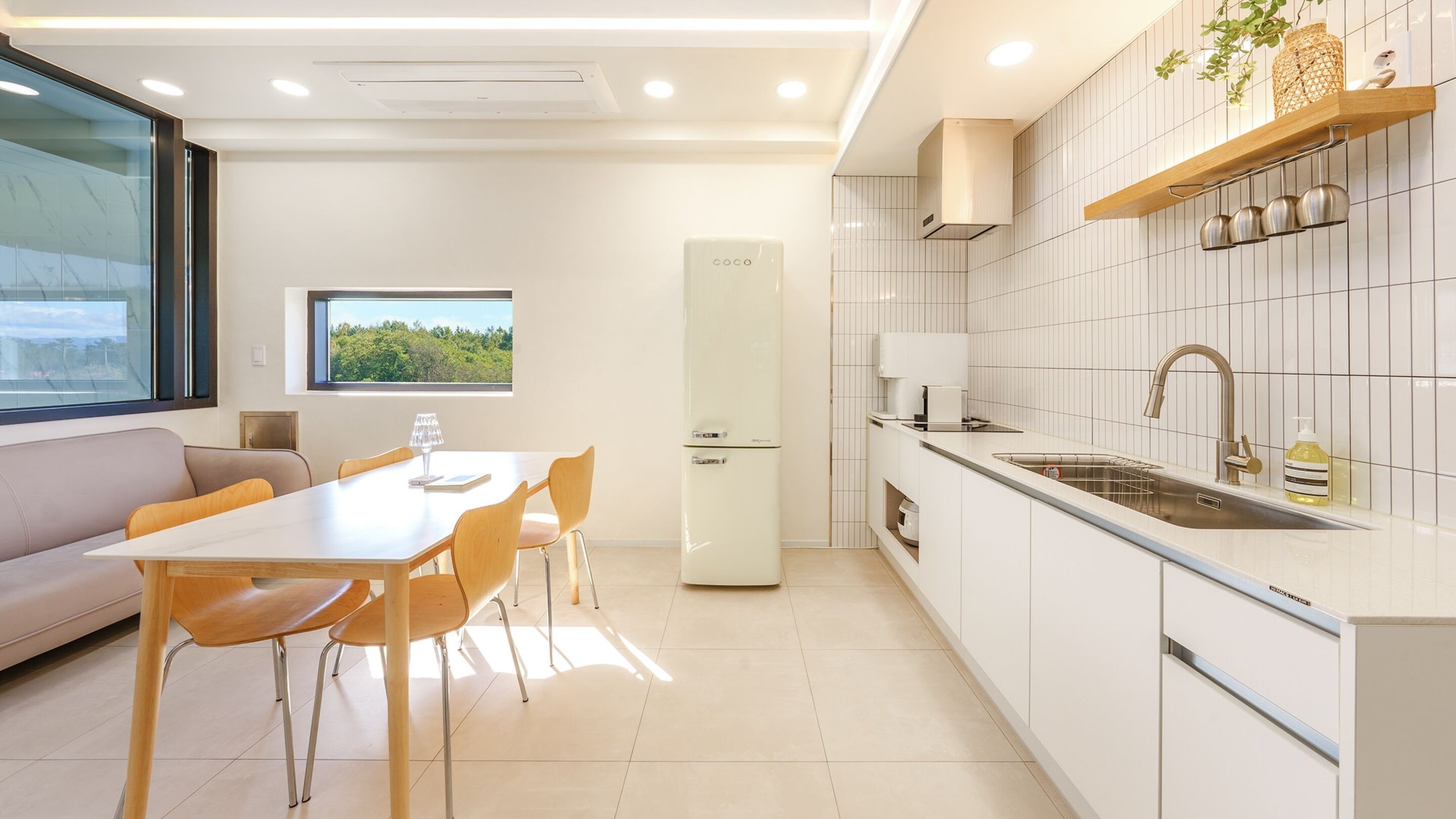 A modern kitchen with white cabinets, a built-in oven, and a stainless steel sink.