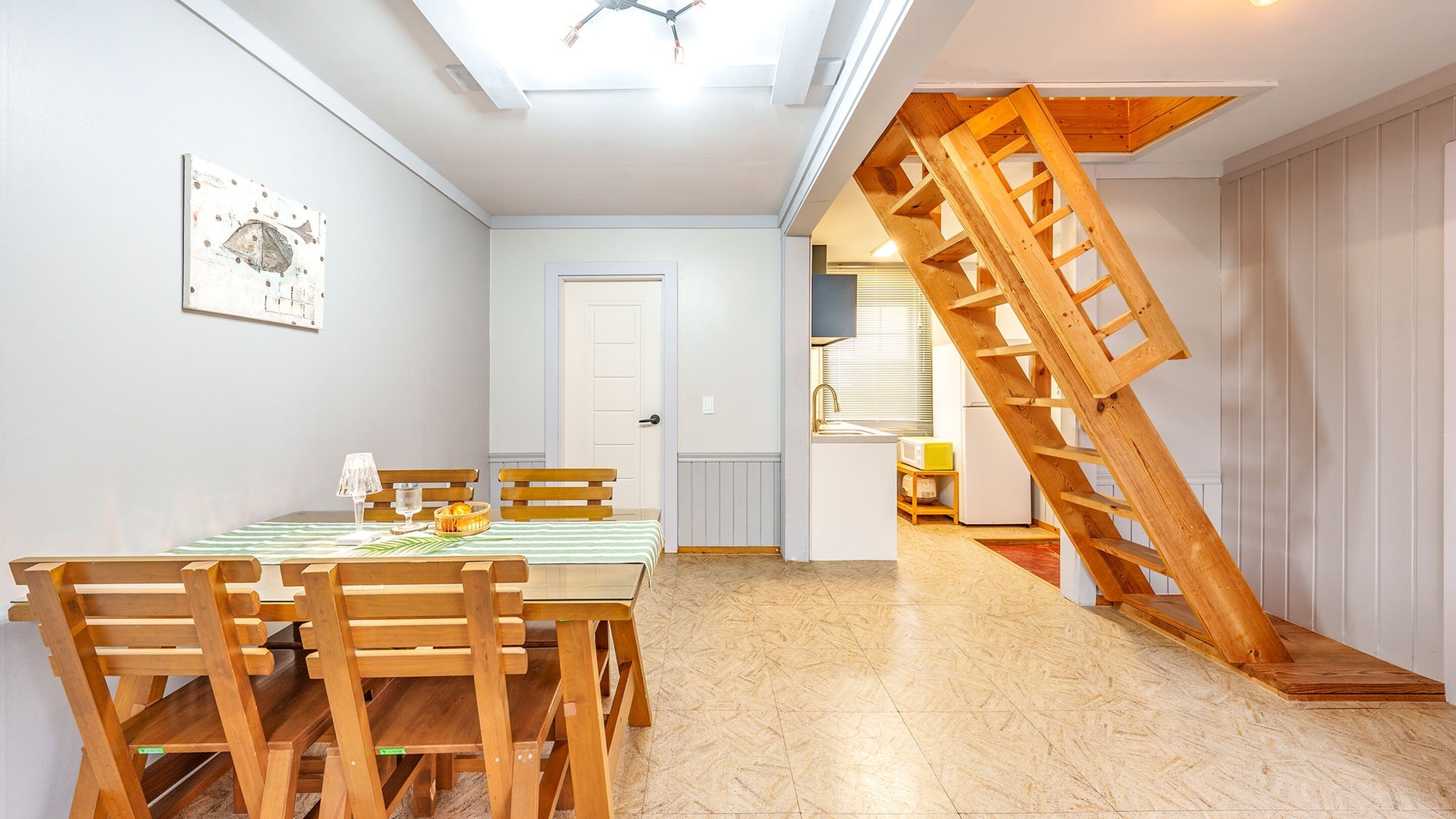 A dining area with a wooden table and chairs, a ceiling fan, and a wooden staircase.