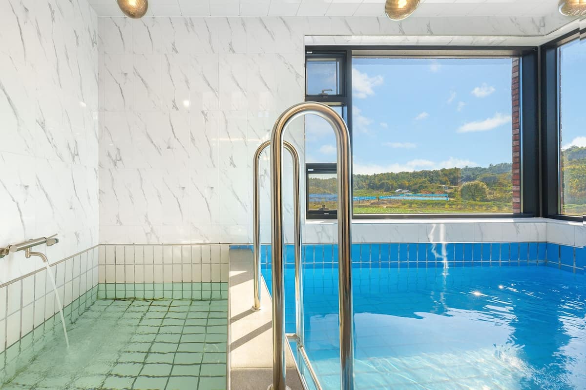 Una piscina con vistas a un paisaje a través de un amplio ventanal.