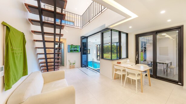 Un intérieur moderne avec un escalier, un coin repas et une porte vitrée donnant sur une piscine.