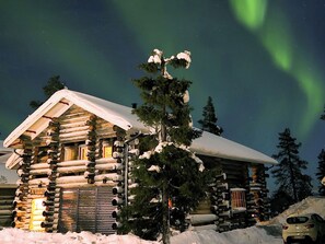 A log cabin with a snow-covered roof, surrounded by trees and a car parked nearby. - Vacation home Luppo by Interhome (Kittilä)