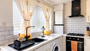 Une cuisine moderne équipée d’un lave-linge intégré, d’une cuisinière à gaz et d’un four à micro-ondes.