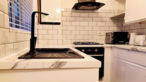 A kitchen with a gas stove, oven, and a microwave. - 2 Bedroom House in Leeds - Sleeps 5, Wifi, Pets (Leeds)