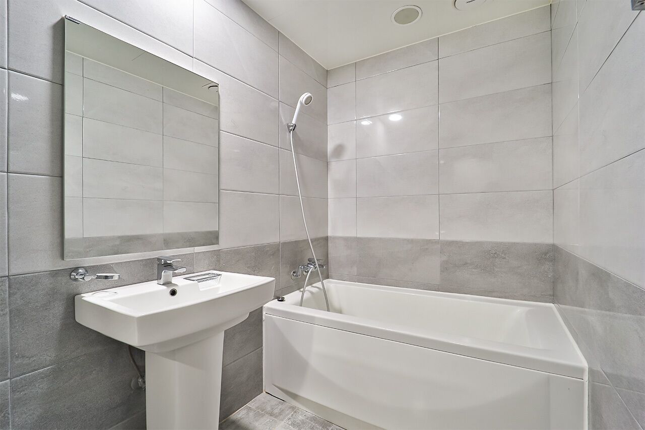 Un bagno moderno con un lavandino bianco, una vasca e un grande specchio.