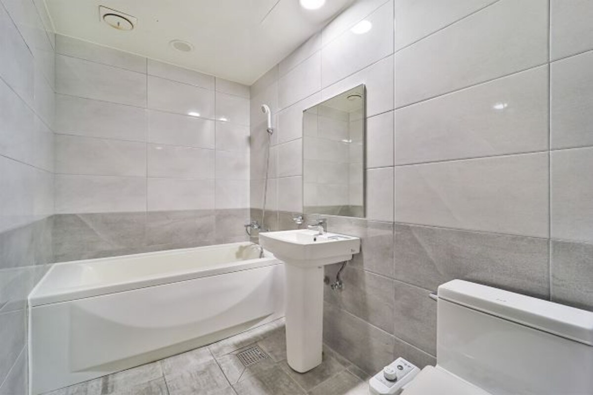 A modern bathroom with a bathtub, a pedestal sink, and a toilet.