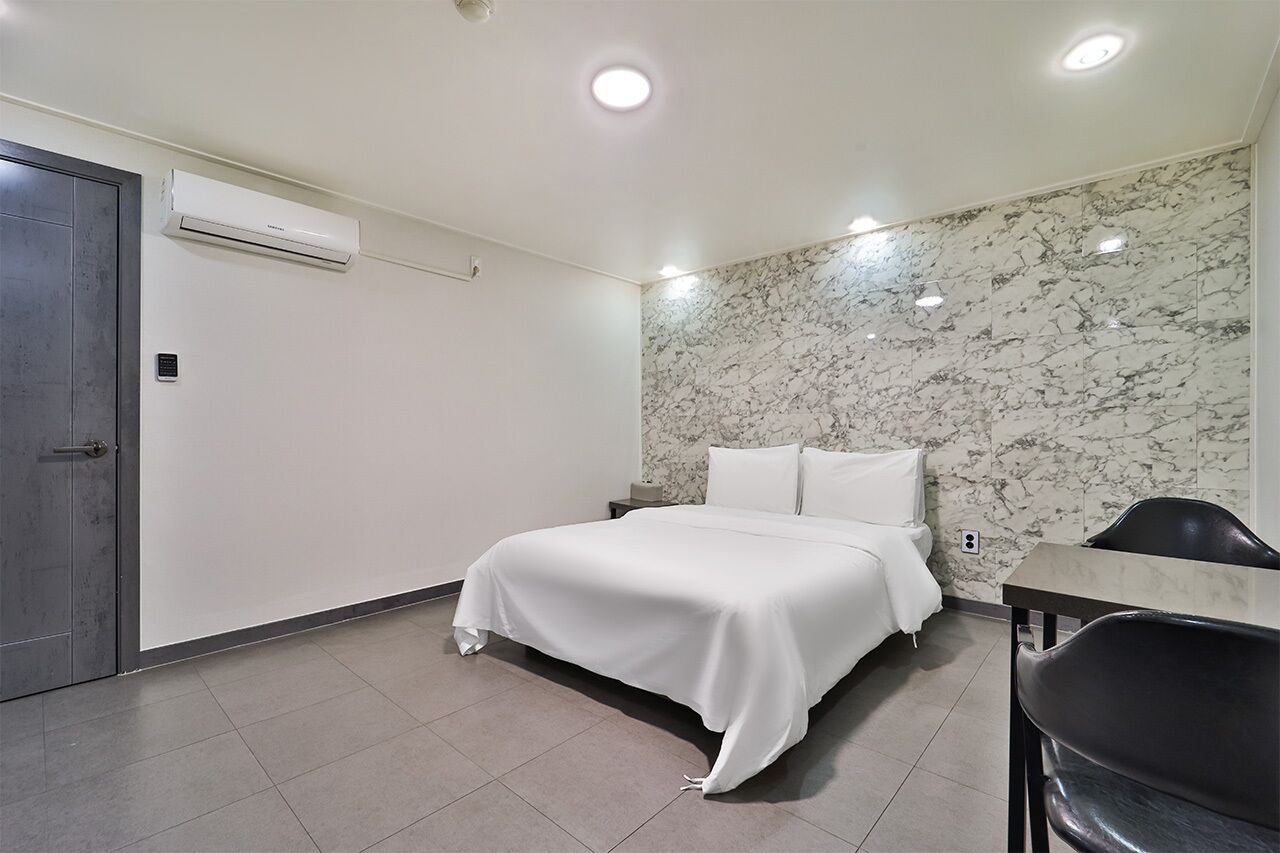 A modern hotel room with a bed, a desk, and a chair.