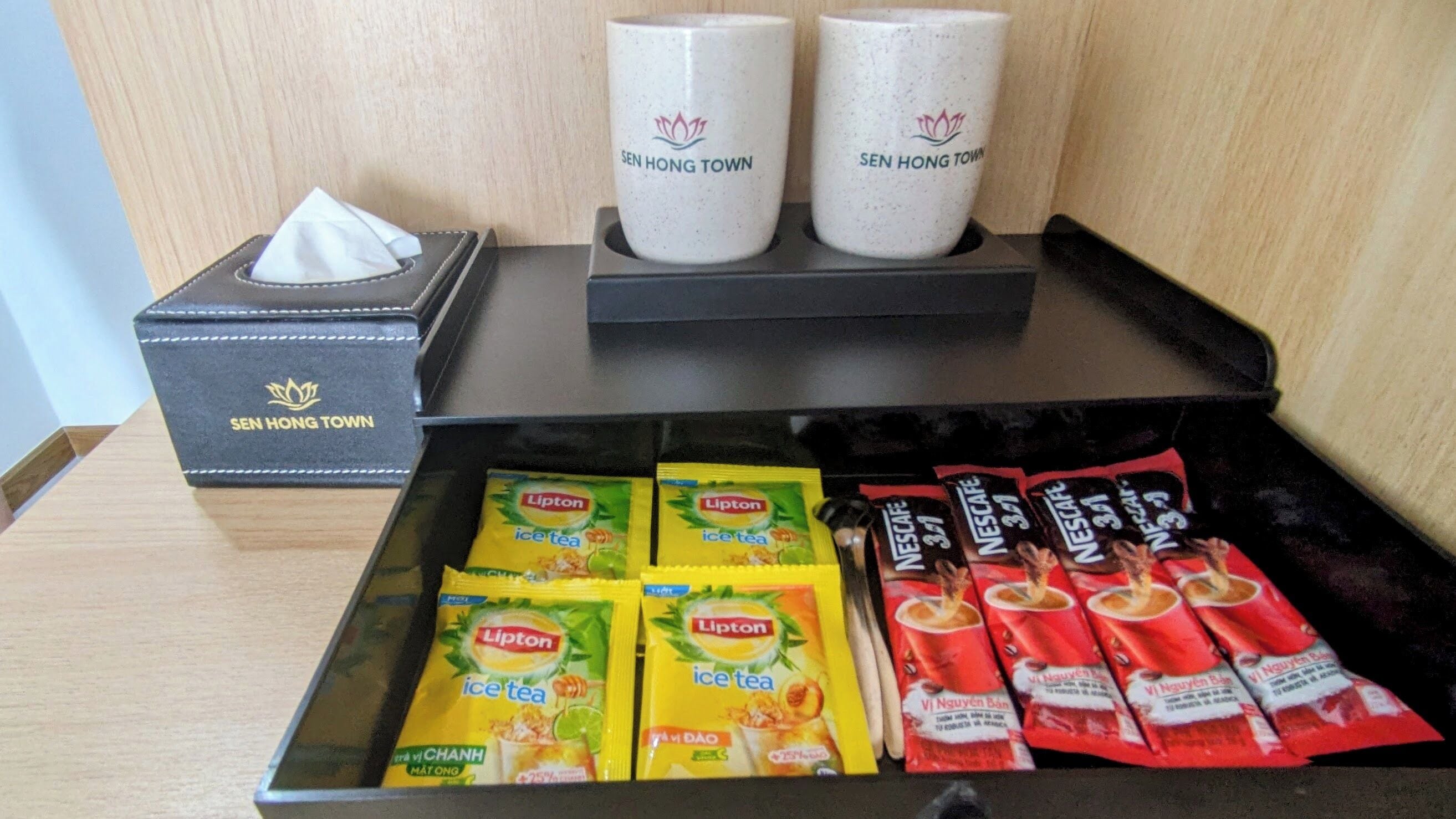 A hotel room with a drawer containing Lipton ice tea packets and Nescafé instant coffee packets.