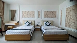A hotel room with two beds, a desk, and a mirror.