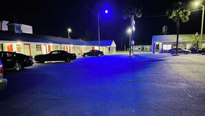Un motel con varias habitaciones, un estacionamiento y algunos coches aparcados.