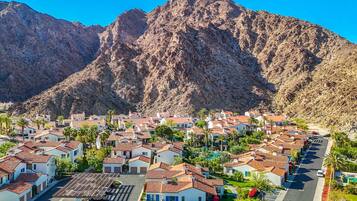 A residential area with houses featuring red-tiled roofs, surrounded by mountains.