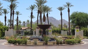 A landscaped area with a central fountain, palm trees, and a mountain in the background. - La Quinta Luxe C | Studio Legacy Villa (La Quinta)