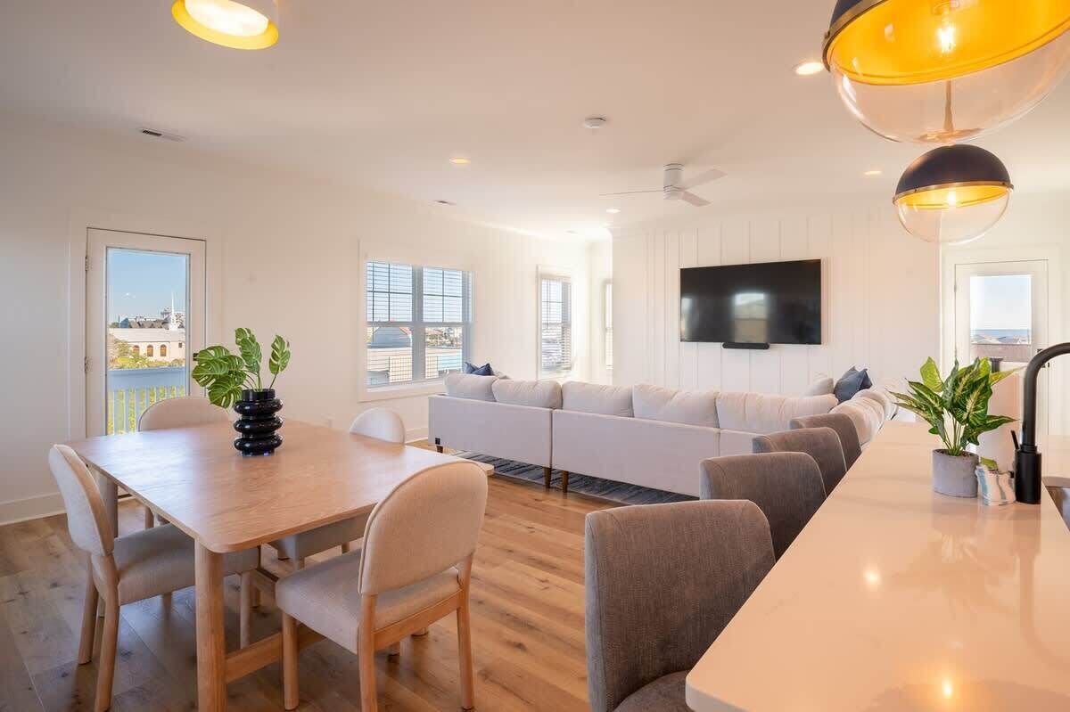 Una sala de estar moderna con un sofá, una mesa de comedor y un televisor montado en la pared.
