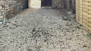 A rustic stone building with a gravel driveway leading to a wooden door. - Loca saiso/vac/Séjour : 120 m² in an authentic, restored farmhouse (Goutrens)