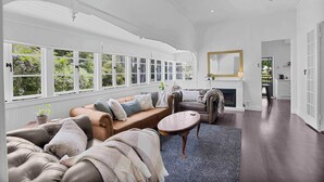 Un salon spacieux doté d’une grande fenêtre, d’une cheminée et d’un ventilateur de plafond.