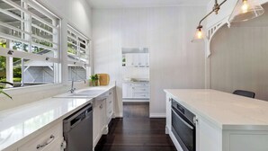 Une cuisine moderne avec des meubles blancs, un lave-vaisselle et une grande fenêtre.