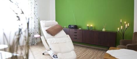 Una habitación moderna con sillón de masaje, una mesa de madera y una pared verde.