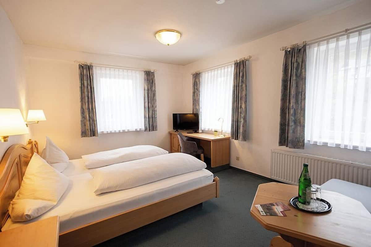 Una habitación de hotel con cama, escritorio, silla y televisor.