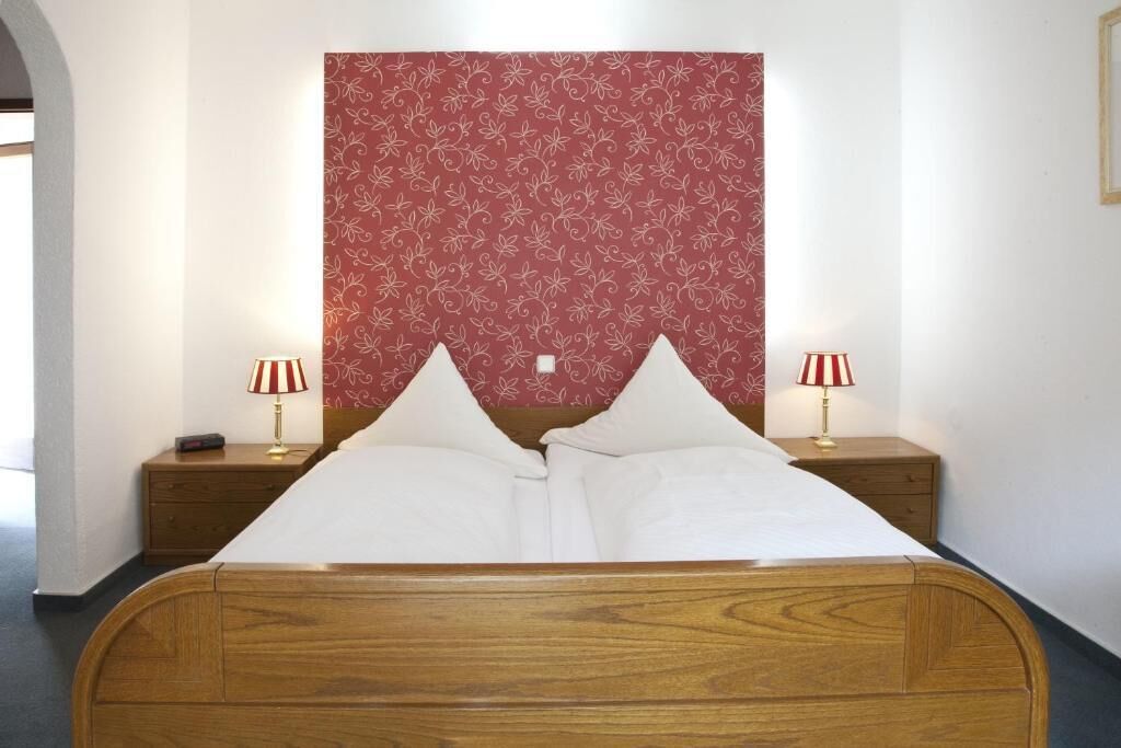 Un lit bien fait, avec deux oreillers, deux lampes de chevet et une tête de lit à motifs floraux.