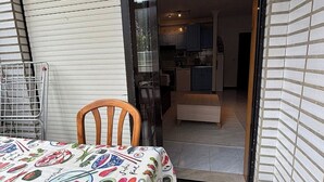 Un pequeño comedor con una mesa dispuesta para dos personas, una silla y una estantería metálica.