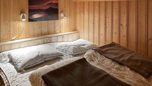 A wooden-paneled room with two beds, each with white bedding and a brown blanket. There are wall-mounted lights and a painting above the beds. - Lovely home in Sjusjøen with WiFi (Sjusjøen)