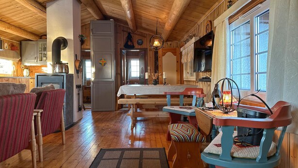 A cozy cabin interior with wooden floors, a dining area, a fireplace, and a television. - Lovely home in Sjusjøen with WiFi (Sjusjøen)
