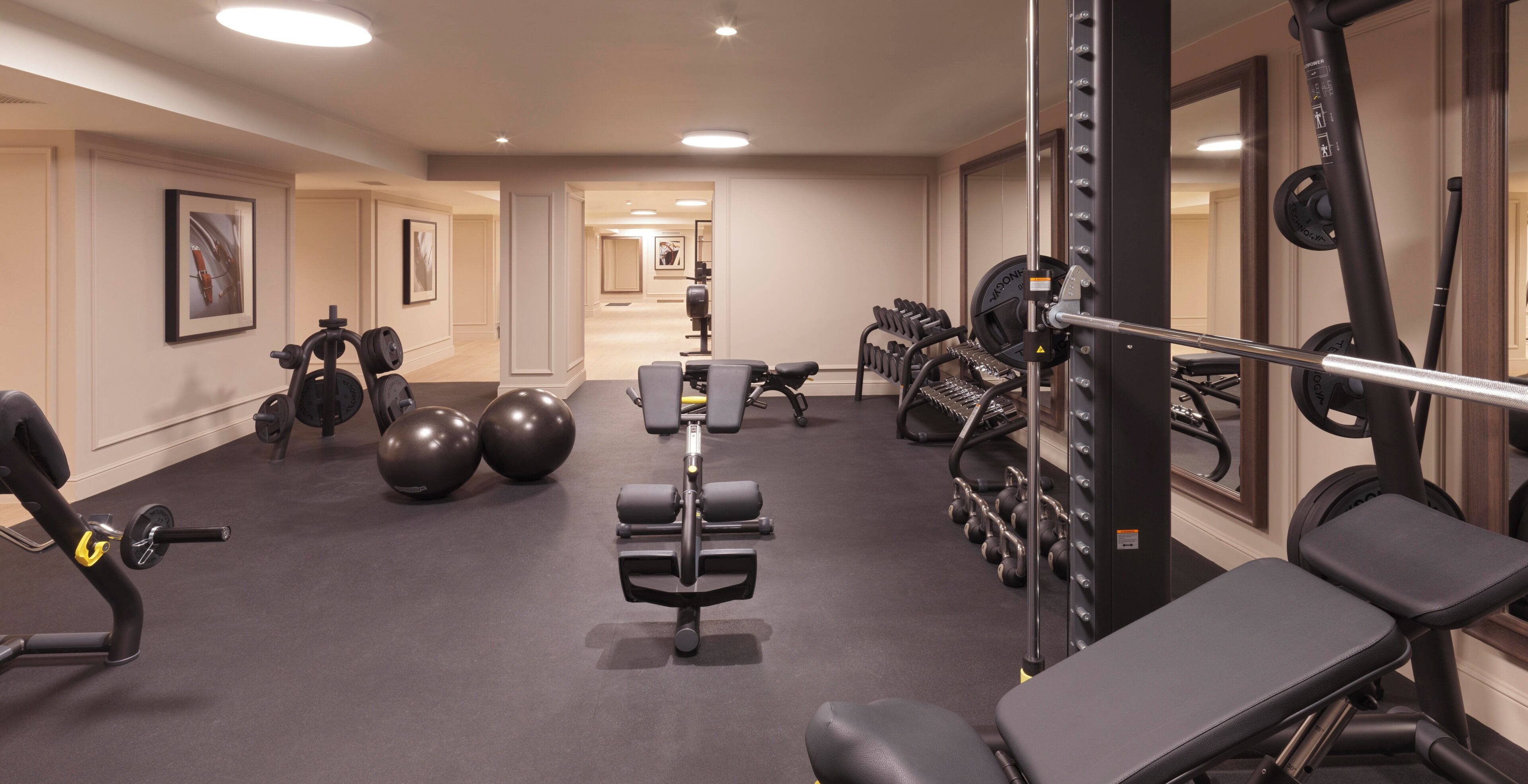 Uma academia com equipamentos de musculação, bolas de exercícios e bancos.