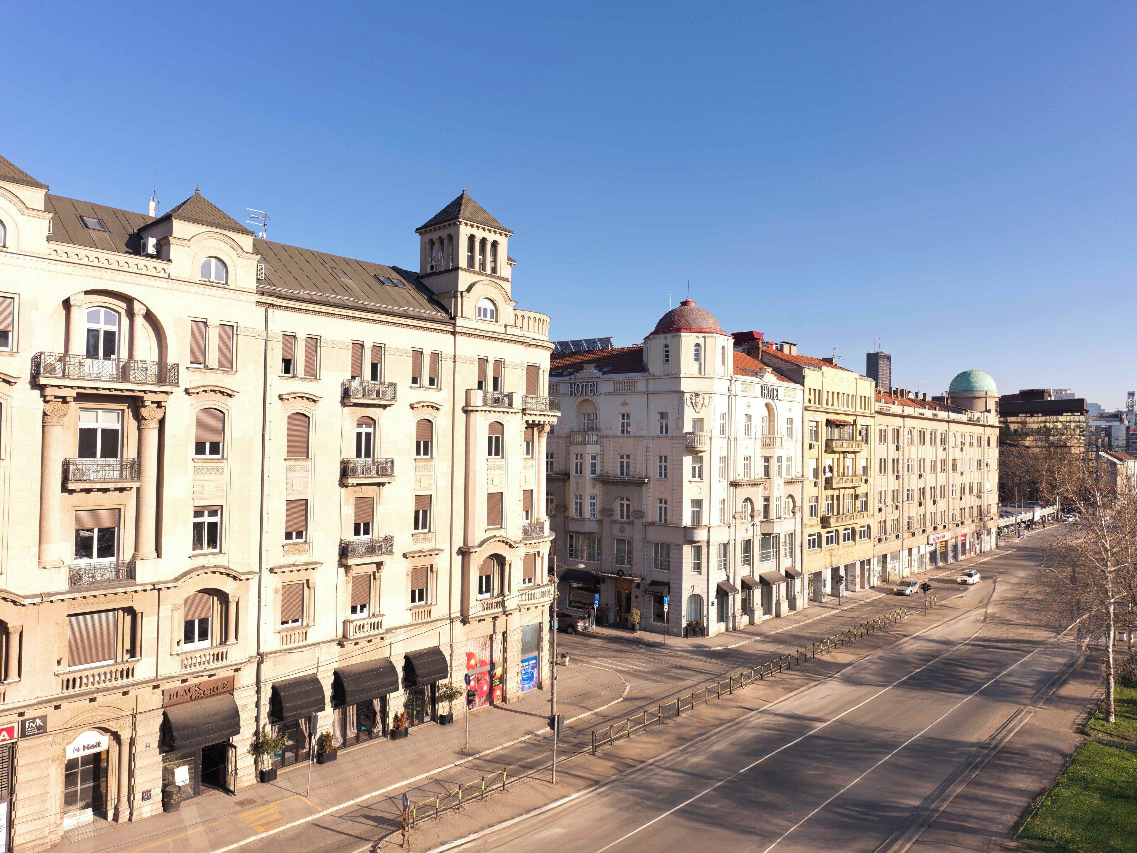 A row of historic buildings with balconies and a central tower, likely part of a hotel complex.