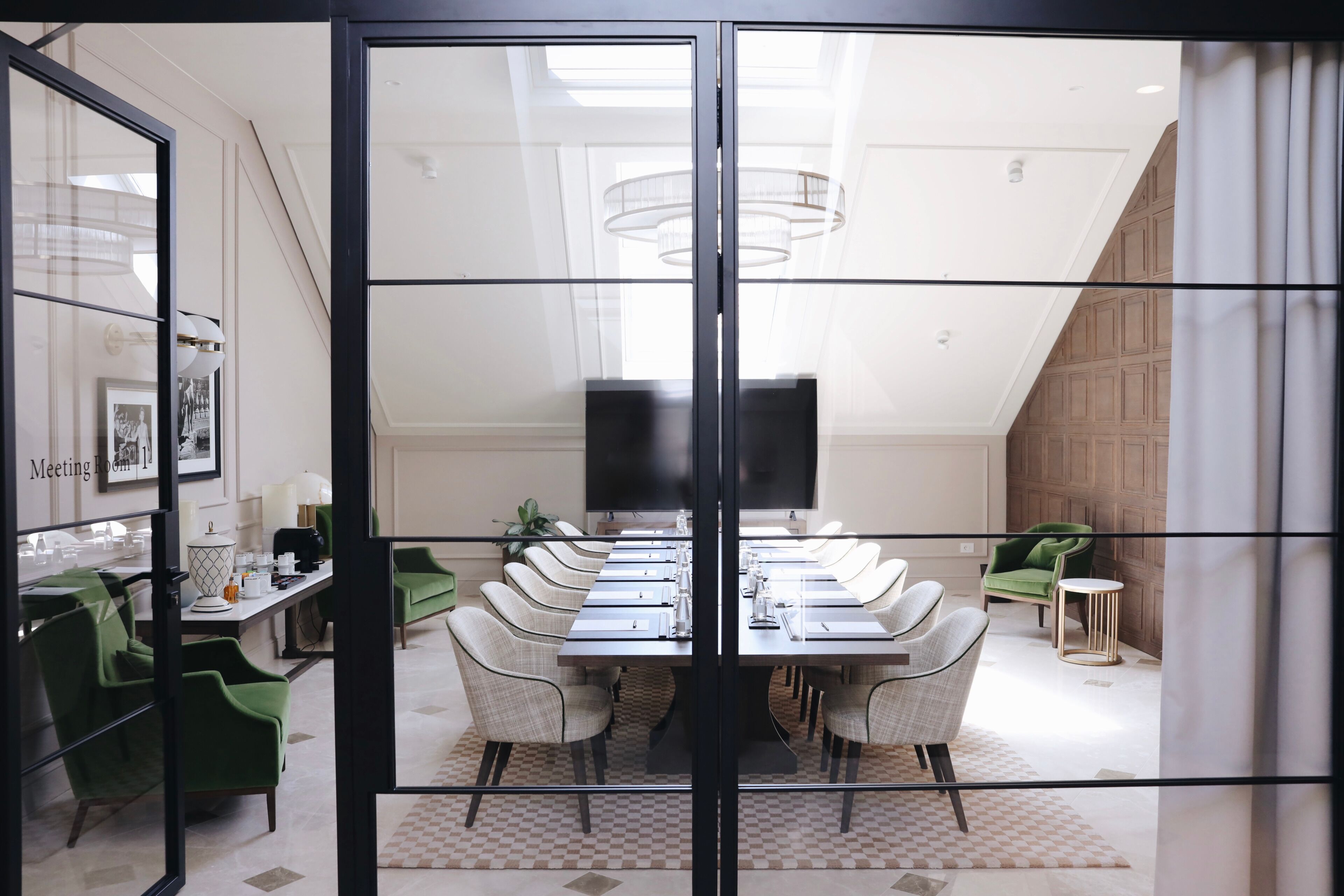 A conference room with a long table, chairs, and a TV screen.