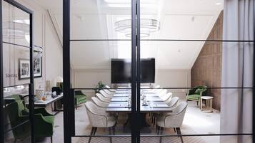 Une salle de conférence avec une longue table, des chaises et un écran de télévision.