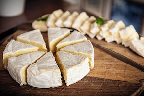 A wheel of cheese cut into wedges on a wooden board. - Phanta Rhei Boutique Hotel (Amsterdam)