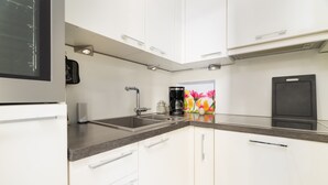 A modern kitchen with white cabinets, a stainless steel sink, and a coffee maker. - Vacation apartment "Peacock" in the recreation center Laboe (Laboe)
