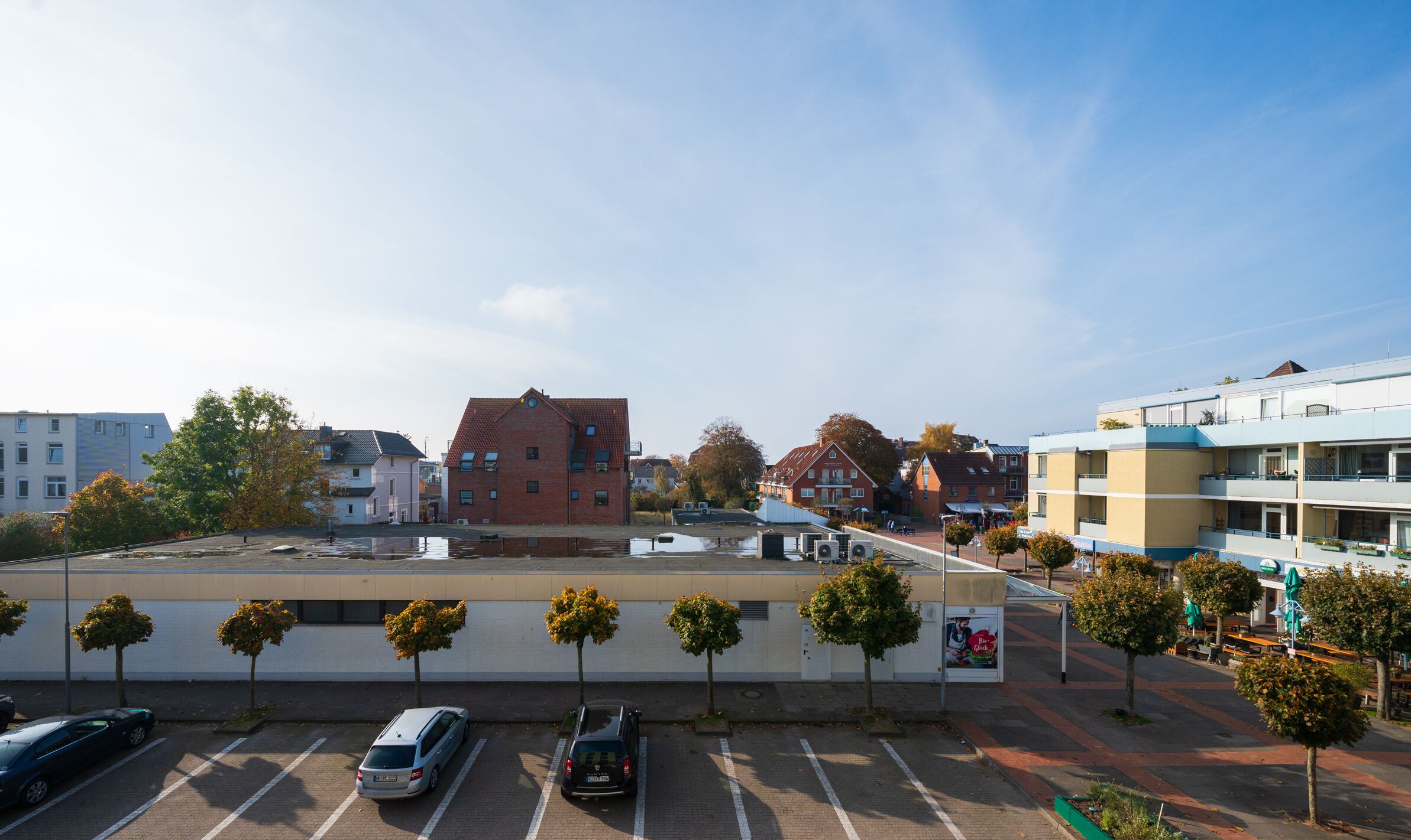 Ein Parkplatz mit mehreren Autos, einer kleinen Kiosk und einer Baumreihe.