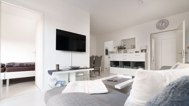 A modern living room with a flat-screen TV, a sofa, a coffee table, and a dining area with chairs and a glass-top table. - Vacation apartment "Peacock" in the recreation center Laboe (Laboe)