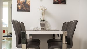 A dining area with a white table, two leather chairs, a vase with white flowers, and two paintings on the wall. - Vacation apartment "Peacock" in the recreation center Laboe (Laboe)