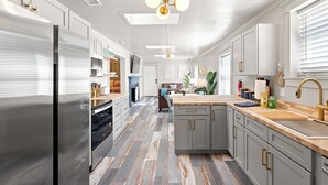 Una cocina moderna con electrodomésticos de acero inoxidable, encimera de madera y una isla central.