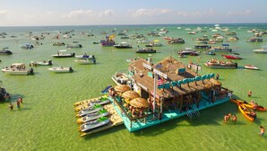 Ein schwimmendes Restaurant mit einem Reetdach, umgeben von einer Marina mit verschiedenen Booten.