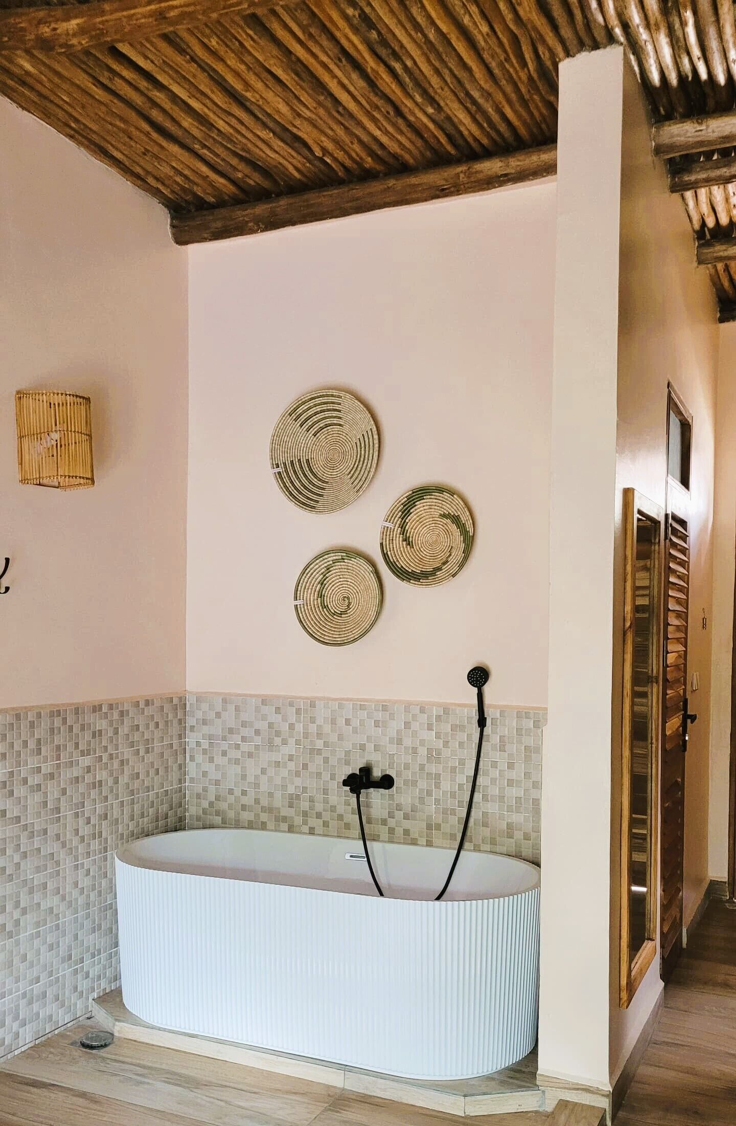 A bathroom with a freestanding bathtub, mosaic tile backsplash, and a wooden ceiling.
