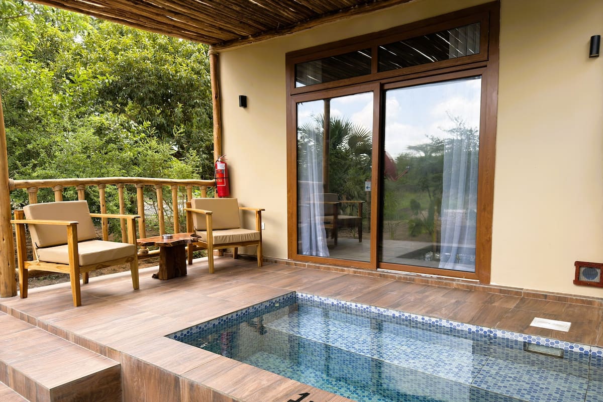 A pool area with a glass enclosure, wooden deck, and outdoor furniture.