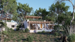 A modern house with a covered patio, surrounded by trees and a grassy area. - Africa Safari Nyerere (Selous Game Reserve)