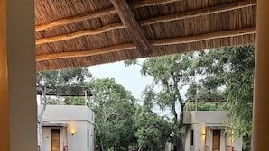 A dining area with a table set for two, overlooking a swimming pool and two buildings in the background. - Africa Safari Nyerere (Selous Game Reserve)
