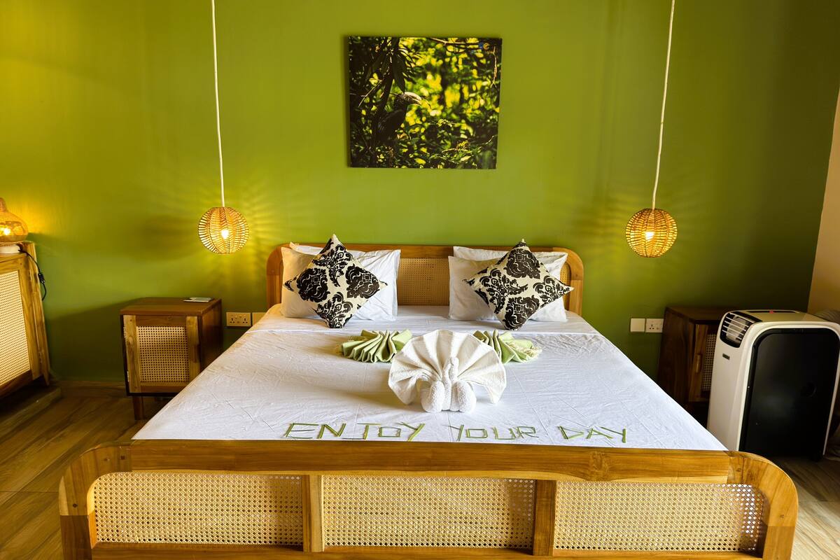 A neatly made bed with a message on the bedspread, two bedside lamps, a wall-mounted picture, and a bedside heater.