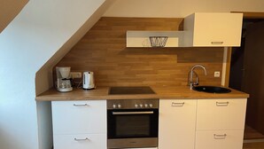 Una cocina compacta con horno integrado, cafetera y lavabo.
