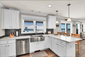 A modern kitchen with white cabinetry, stainless steel appliances, and a large window providing a view.