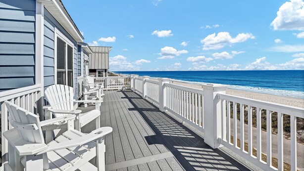 A wooden deck with white railings and Adirondack chairs overlooking a beach. - Slow down, unwind, and soak up "Topsail Time" (North Topsail Beach)