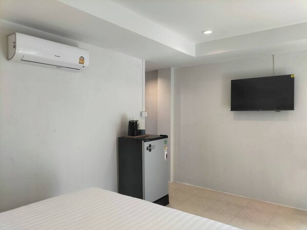 Une chambre d’hôtel équipée d’un lit, d’un minibar, d’une télévision à écran plat et de la climatisation.