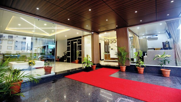 Een hotel lobby met een rode loper, potplanten en een modern plafondontwerp.