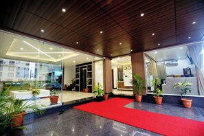Un hall de hotel con alfombra roja, plantas en macetas y un diseño de techo moderno.